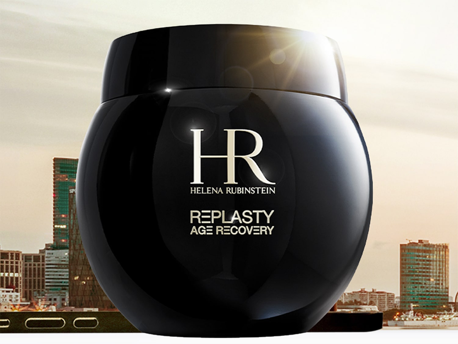 Czarny słoik kremu Helena Rubinstein Replasty Age Recovery na tle miasta.