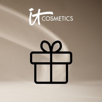 Logo IT Cosmetics z czarnym symbolem prezentu na rozmytym beżowym tle.
