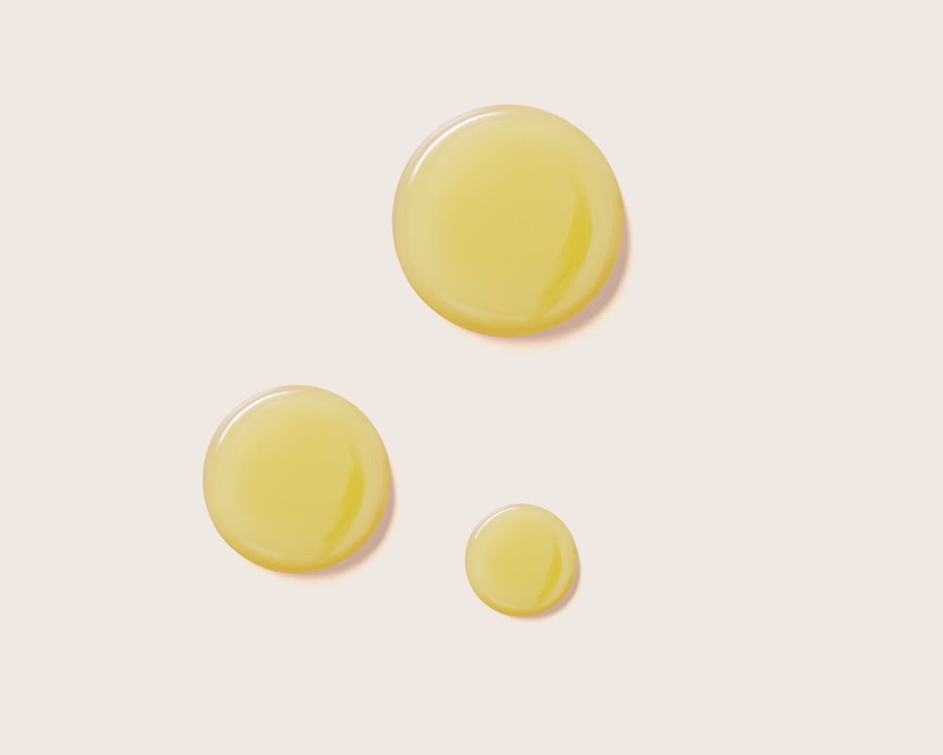 Tres gotas de aceite amarillo claro sobre un fondo color crema, mostrando la textura y consistencia del producto.