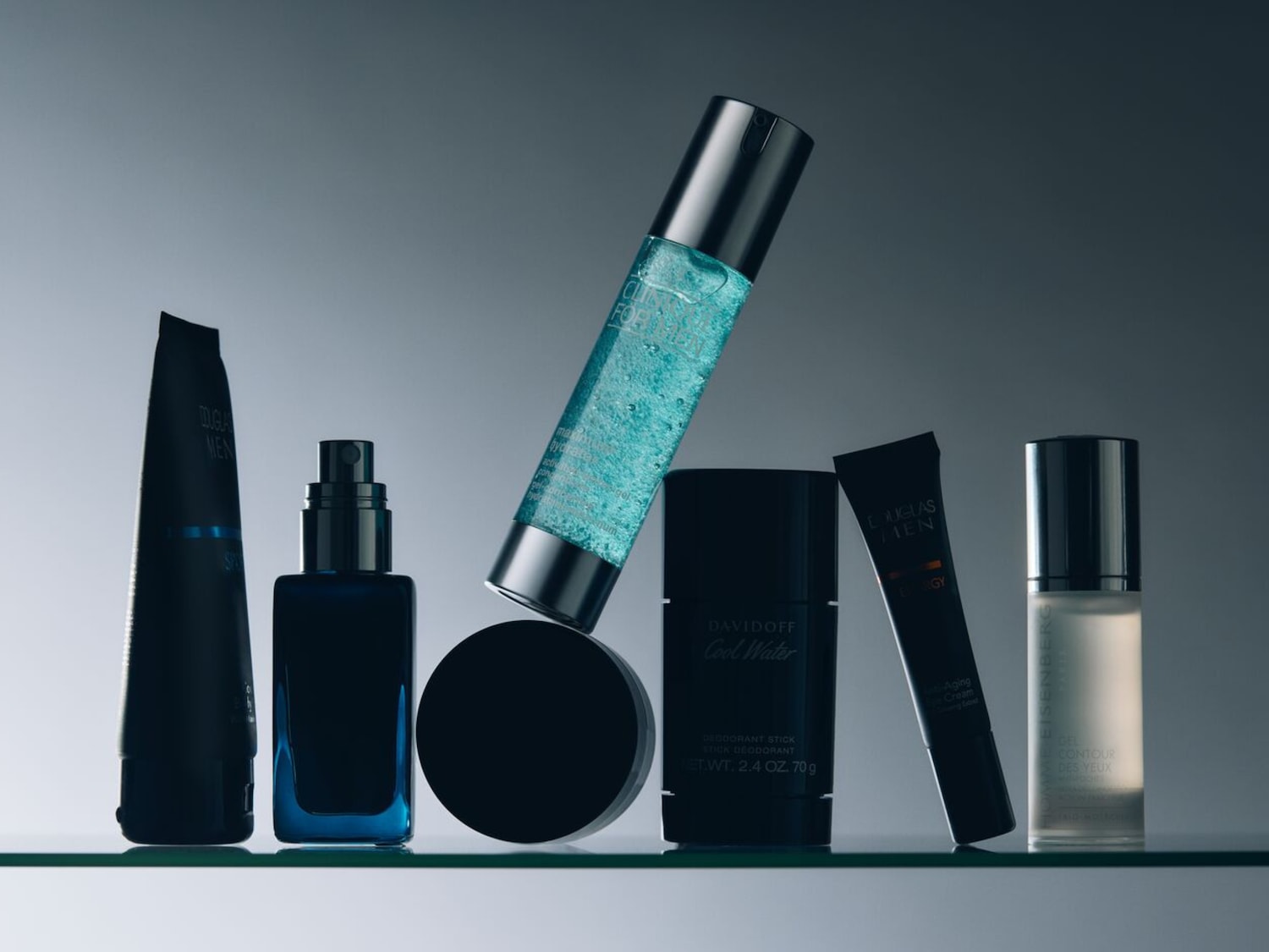 Een verzameling verzorgingsproducten voor mannen, waaronder Douglas Men- en Davidoff Cool Water-deodorant, gepresenteerd in blauwe en zwarte verpakkingen.