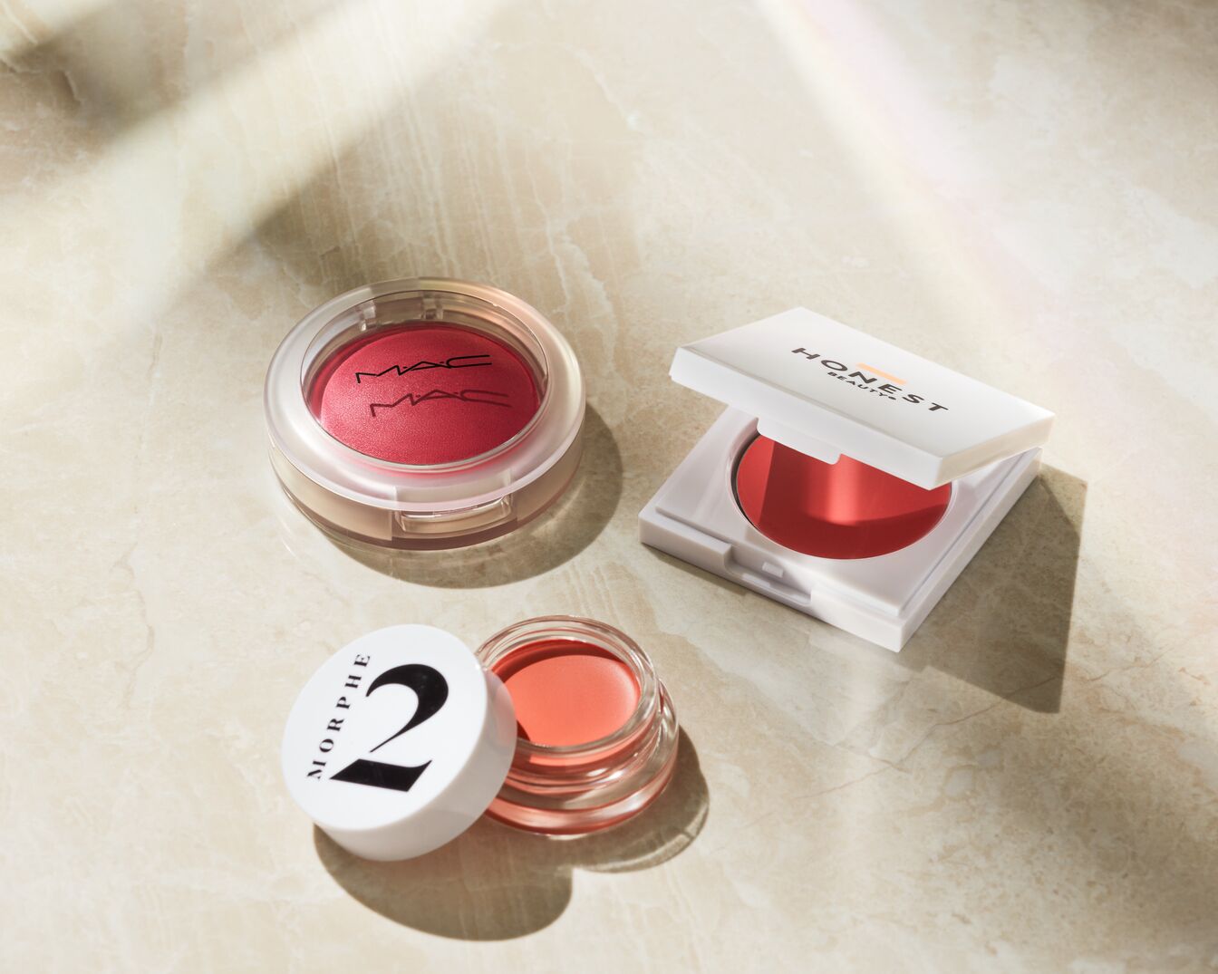 Entdecke MAC Rouge in transparenter Dose, Honest Beauty Rouge in weißer Dose und Morphe 2 Rouge in durchsichtiger Dose mit weißem Deckel für einen frischen Look.