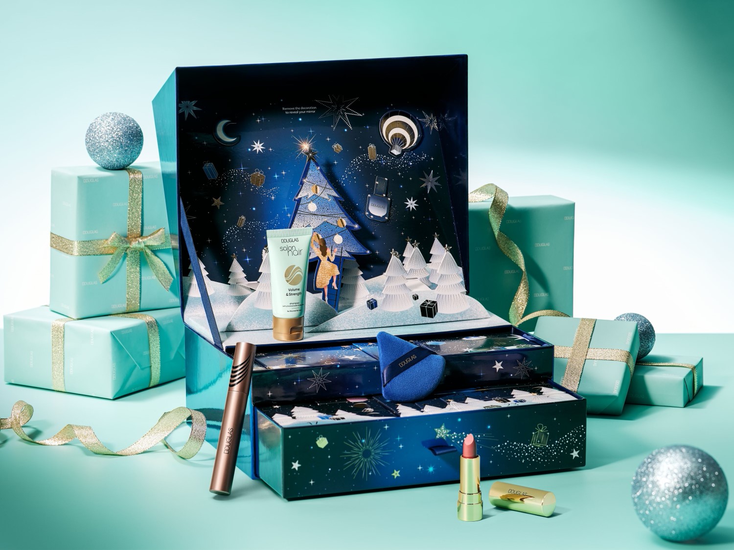 Darčeková súprava Douglas obsahuje rúž, maskaru, šampón na vlasy a hubku na make-up, všetko v slávnostnom balení s vianočným stromčekom a hviezdami.