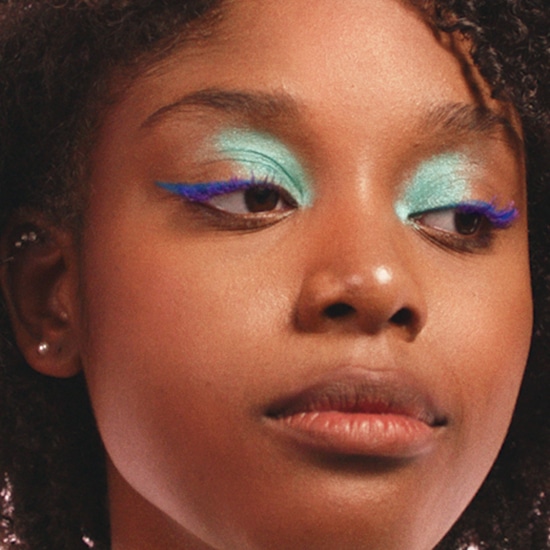 Nahaufnahme eines Mädchens mit hellgrünem Lidschatten und blauem Eyeliner.