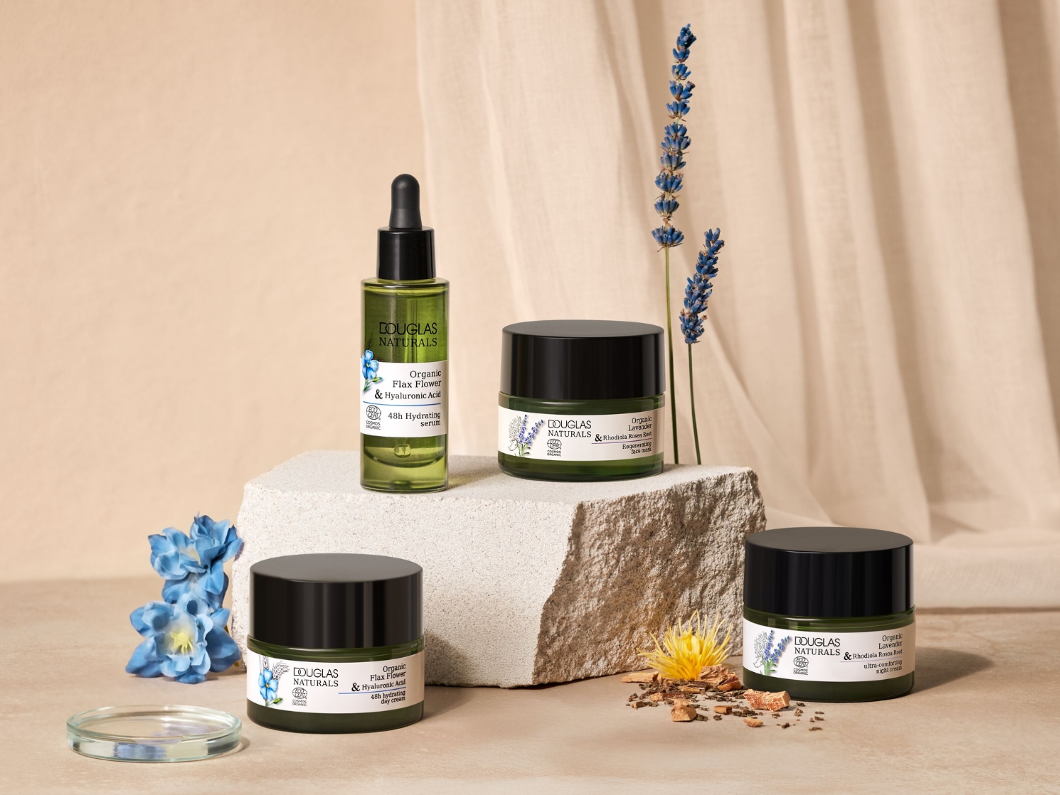 Douglas Naturals Organic Flax Flower & Hyaluronic Acid 48h Hydrating Serum to zielona butelka z pipetą, stojąca na beżowym tle, obok suszonych kwiatów lawendy.
