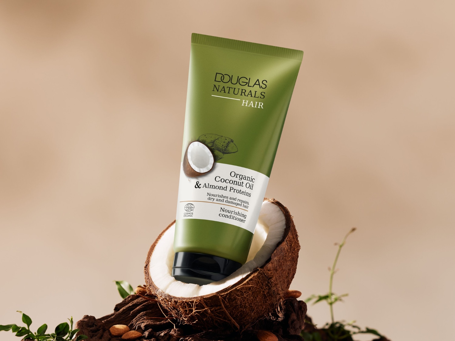 Odżywka do włosów Douglas Naturals z organicznym olejem kokosowym i proteinami migdałowymi, w zielonej tubce, umieszczona jest na tle rozłupanego orzecha kokosowego, co podkreśla jej naturalny skład.