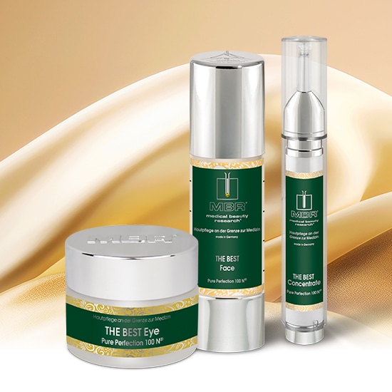 Trzy srebrne pojemniki z zielonymi etykietami MBR The Best Eye, Face i Concentrate Pure Perfection 100 N na złotym tle.