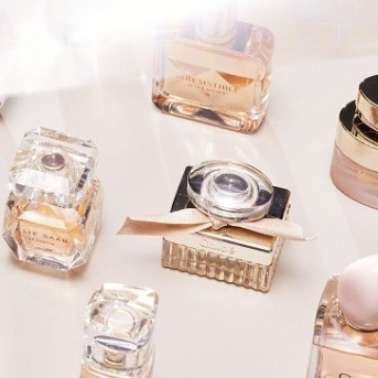 Różne flakony perfum, w tym przezroczyste i złote buteleczki marek takich jak Chloé i Elie Saab, tworzą elegancką kompozycję.