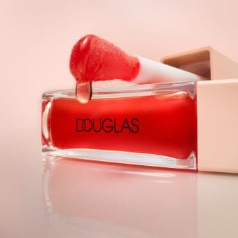 Nahaufnahme eines Douglas Lipglosses mit roter Flüssigkeit und Applikator, der einen glänzenden Tropfen bildet.