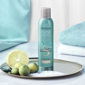 Douglas Home Spa Duschschaum La Rèzidance Seathalasso mit Bergamotte und Mineralien in einer blaugrünen Flasche, umgeben von Limetten und Badesalz.