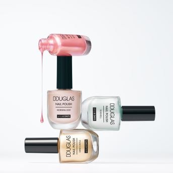 Verschiedene Douglas Nagellacke sind übereinander gestapelt, wobei der oberste rosa ist und ein paar Tropfen Nagellack herauslaufen.