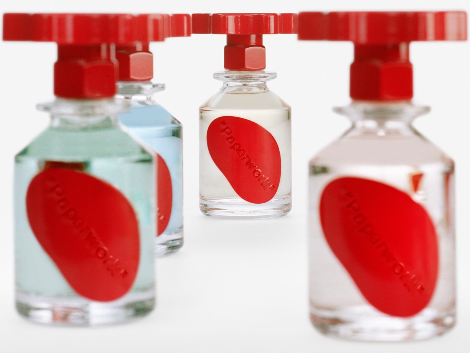 Flakony perfum Paperwork o różnych odcieniach płynów, zamknięte korkami w kształcie czerwonych zaworów, prezentują się nowocześnie i minimalistycznie.