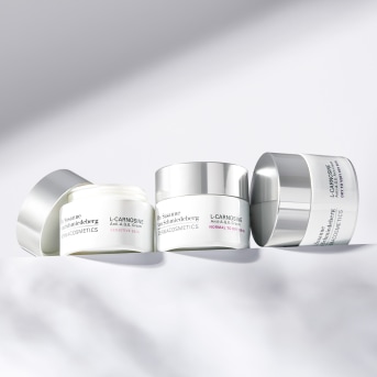 Tre barattoli di crema L-Carnosine con tappi argentati, ideali per pelli normali e sensibili.