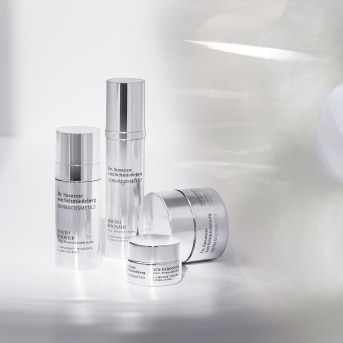 Una collezione di prodotti per la cura della pelle Dr. Susanne von Schmiedeberg DERMACOSMETICS in confezioni argentate di varie dimensioni.