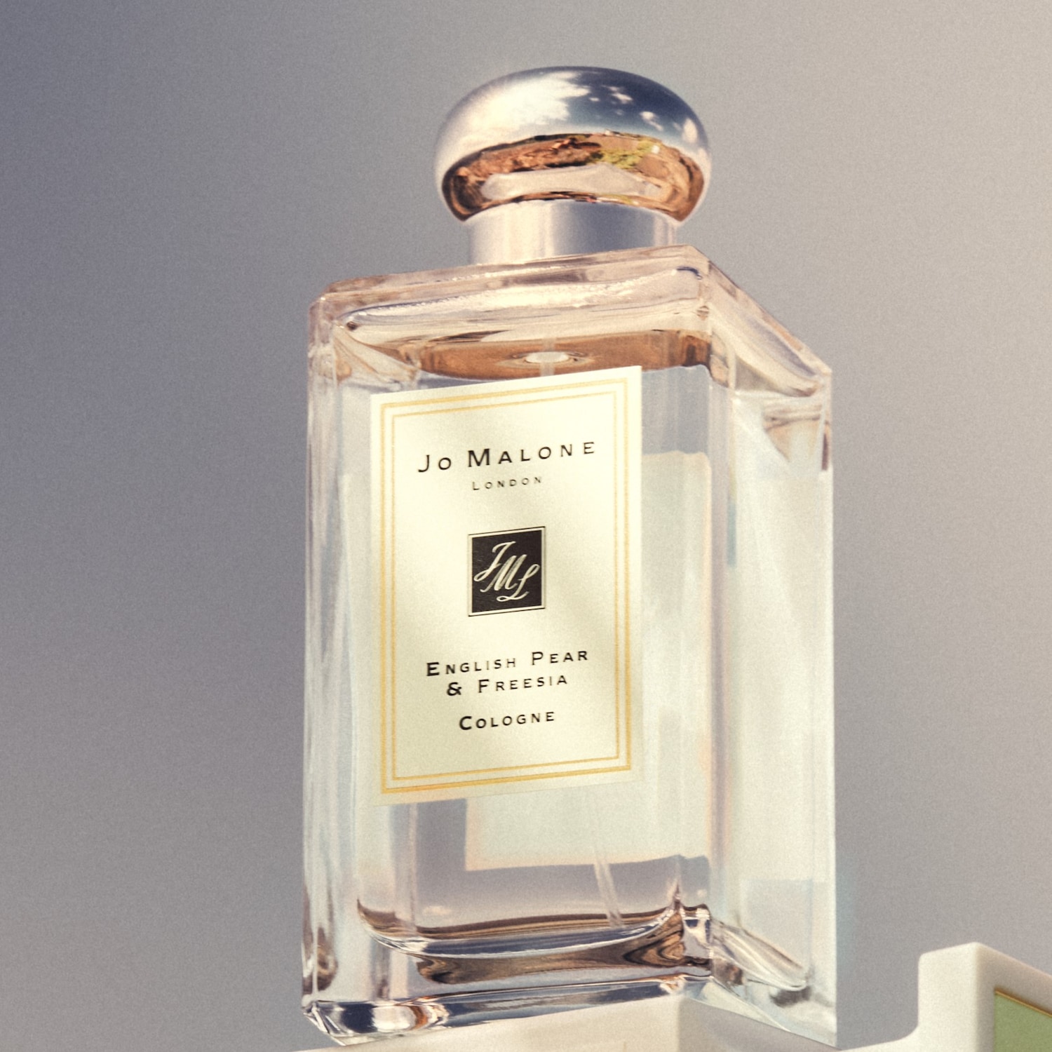 Eine durchsichtige, rechteckige Flasche Jo Malone London English Pear & Freesia Cologne mit silbernem Verschluss.