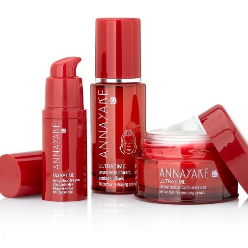 Entdecken Sie Annayake Ultratime: Augenpflege, restrukturierendes Serum und Anti-Falten-Creme in eleganten roten Verpackungen für eine umfassende Hautpflege.