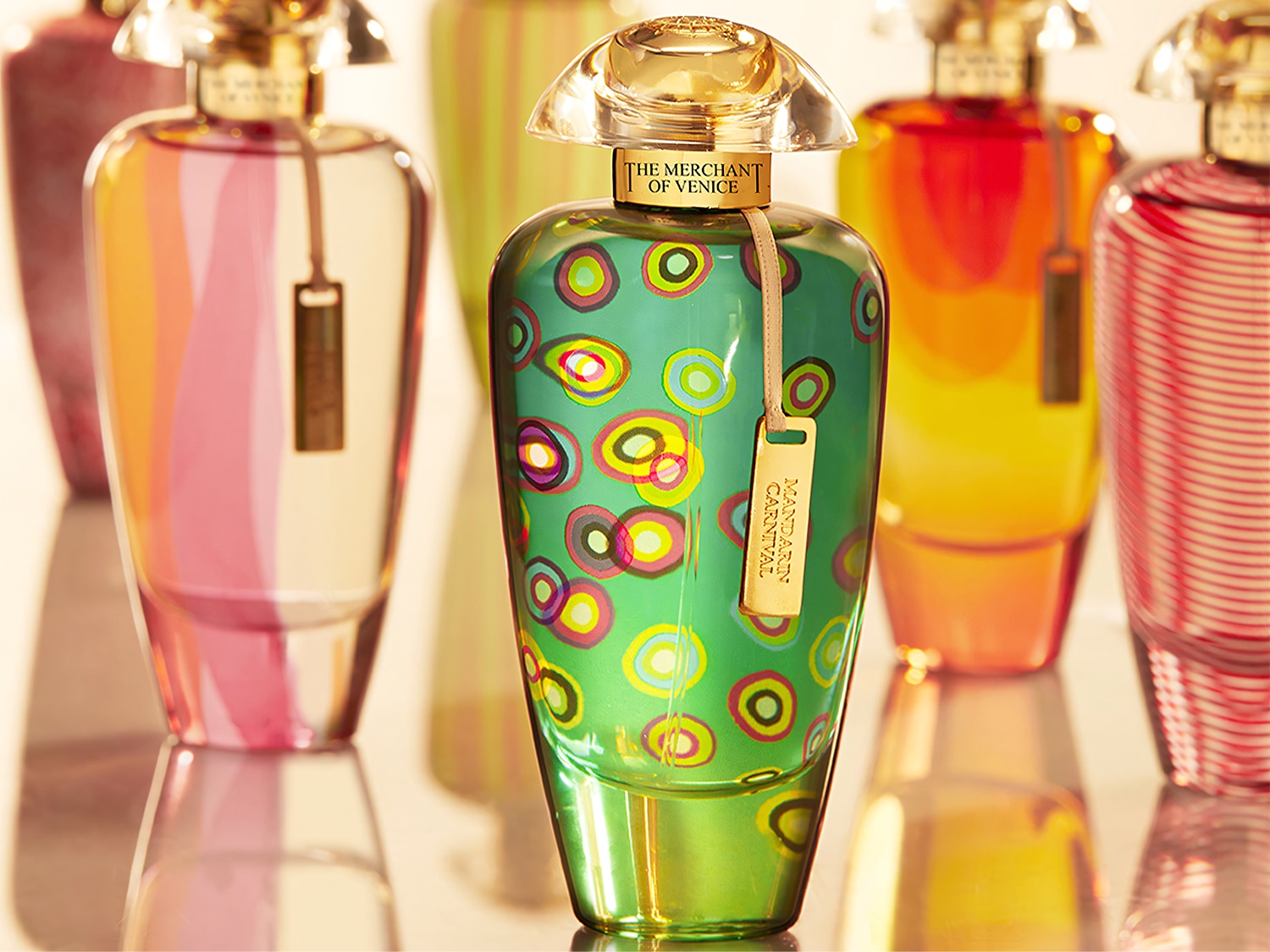 Eleganckie flakony perfum The Merchant of Venice w różnych kolorach i wzorach, z przezroczystymi korkami i złotymi zawieszkami, tworzą luksusową kolekcję.