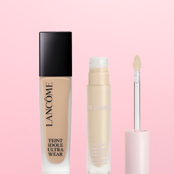 Kremowy podkład Lancôme Teint Idole Ultra Wear w szklanej butelce z czarną nakrętką oraz korektor do twarzy w plastikowym opakowaniu z aplikatorem.