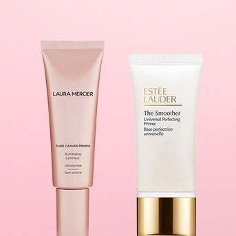 Dwa primery do twarzy: Laura Mercier Pure Canvas Primer w jasnoróżowym opakowaniu i Estee Lauder The Smoother w białym opakowaniu ze złotą nakrętką.