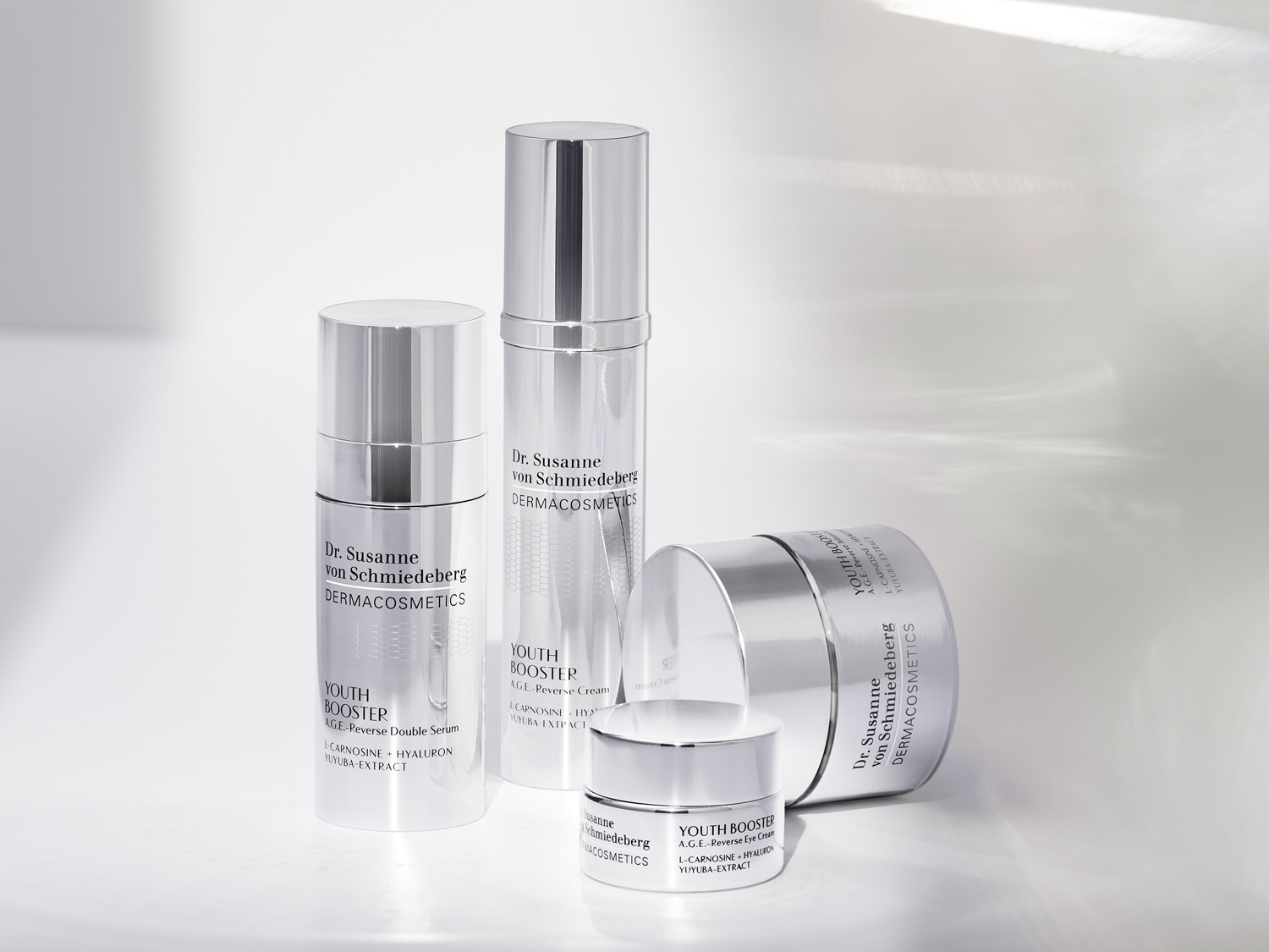 Dr. Susanne von Schmiedeberg DERMACOSMETICS termékei ezüst színű csomagolásban, köztük Youth Booster A.G.E. Reverse Double Serum, krém és szemkrém.