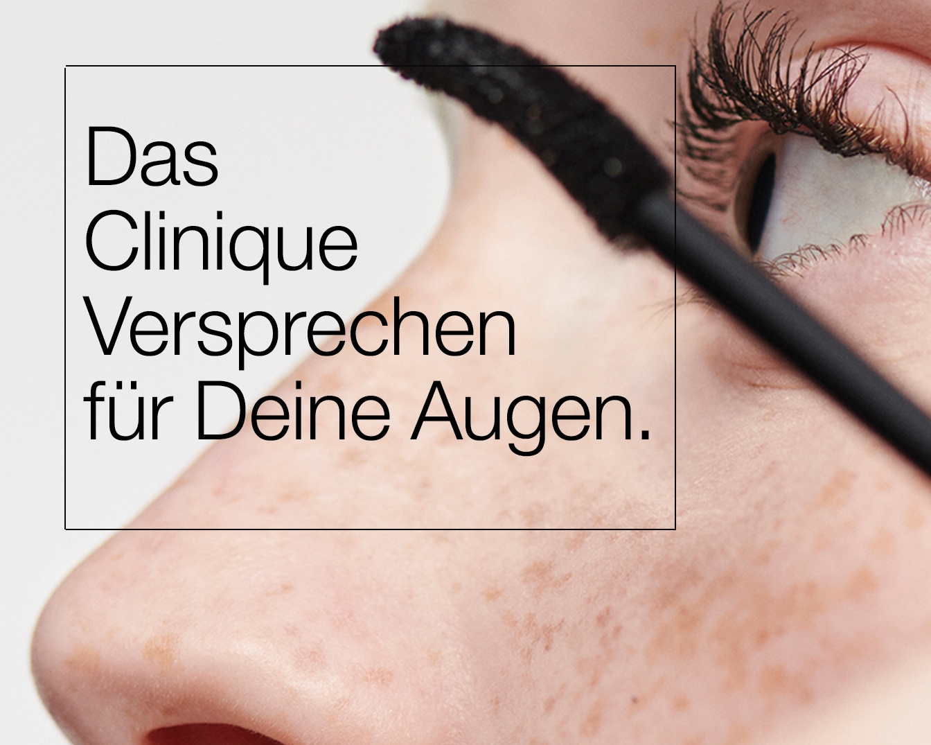 Nahaufnahme eines Auges, während eine Person mit einer schwarzen Mascara-Bürste die Wimpern tuscht. Text im Bild lautet: Das Clinique Versprechen für Deine Augen.