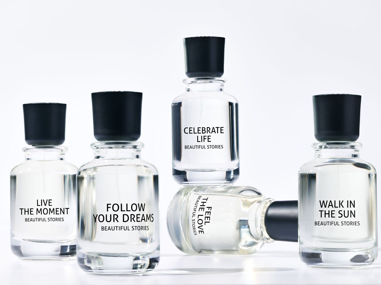 Átlátszó üvegpalackok fekete kupakkal, mindegyiken más-más felirat: "Éld meg a pillanatot", "Kövesd az álmaidat", "Ünnepeld az életet", "Sétálj a napfényben" és "Érezd a szeretetet".