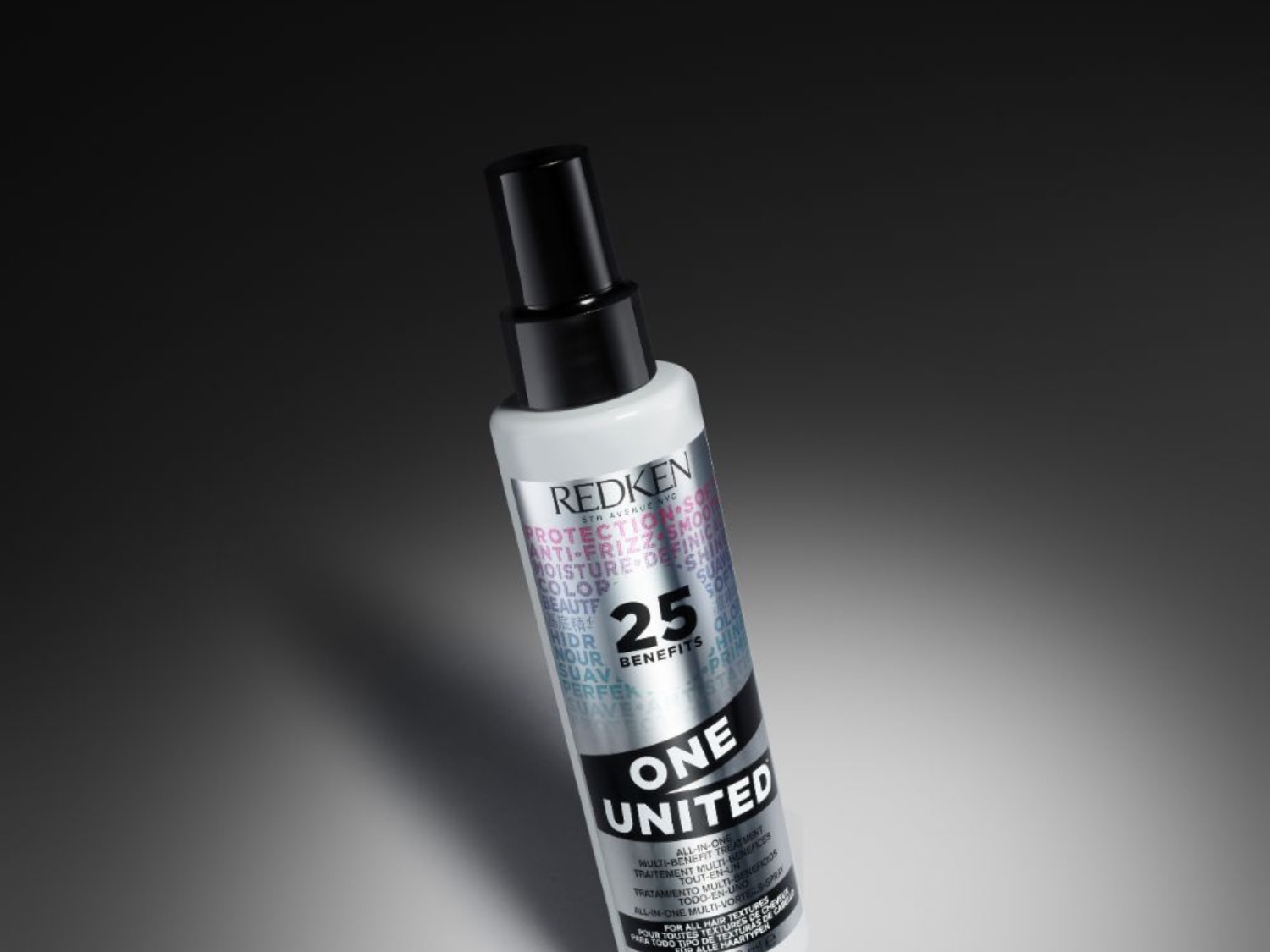 Bílý sprej na vlasy Redken One United s černým dávkovačem slibuje 25 benefitů pro všechny typy vlasů, včetně ochrany, hydratace a lesku.