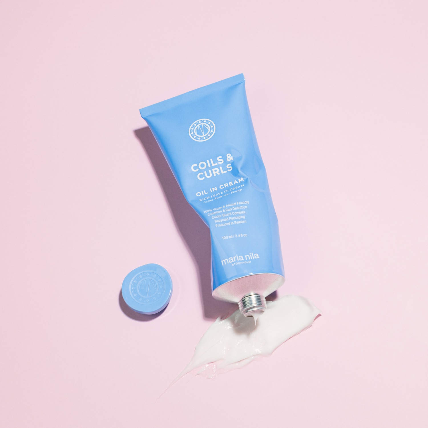 Die Maria Nila Coils & Curls Oil in Cream, präsentiert in einer hellblauen Tube mit weißer Schrift, verspricht reichhaltige Pflege für Locken, ist vegan, tierversuchsfrei und wird in Schweden hergestellt.