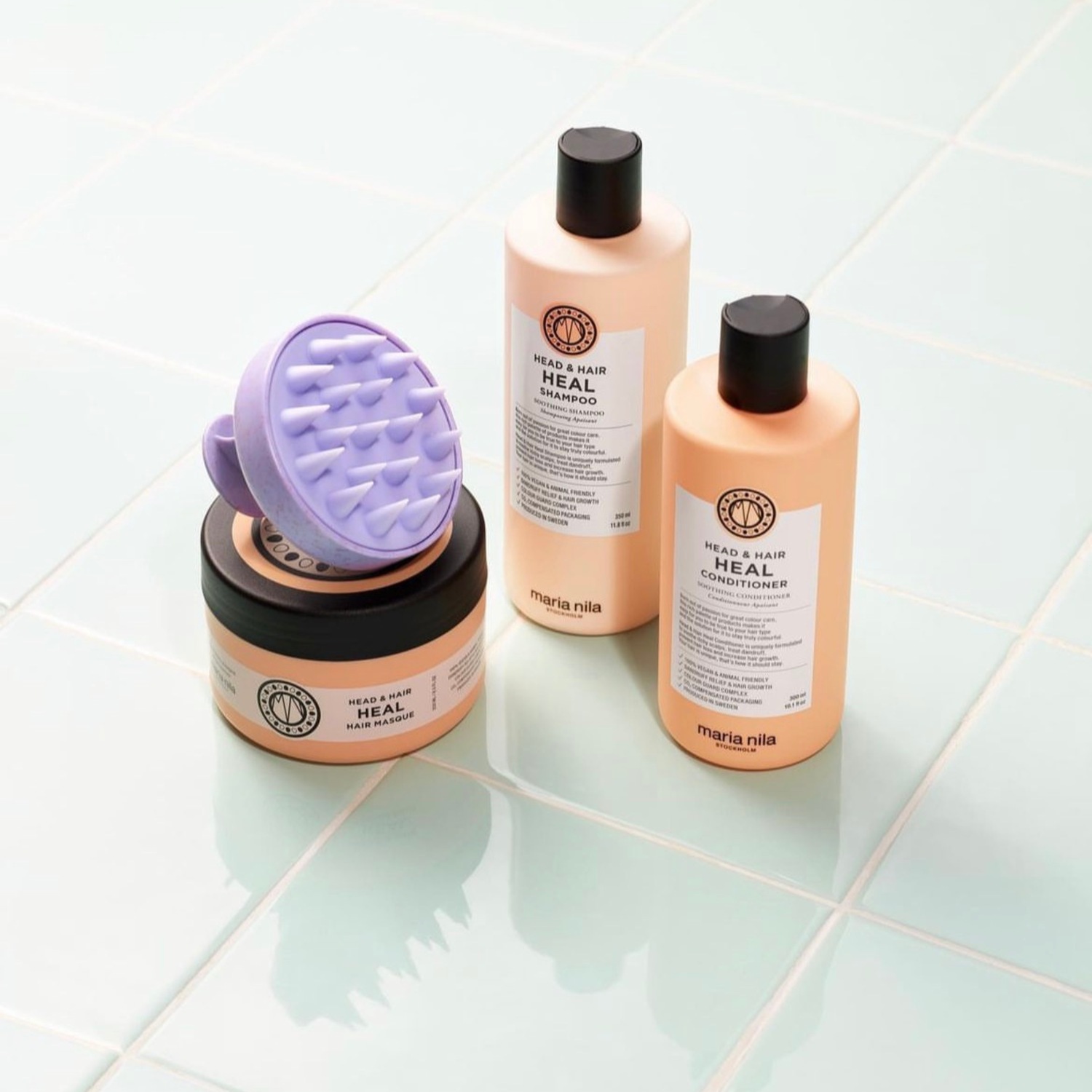 Maria Nila Head & Hair Heal Kollektion mit Shampoo, Conditioner, Haarmaske und Kopfhautmassagebürste für eine beruhigende Haarpflege.