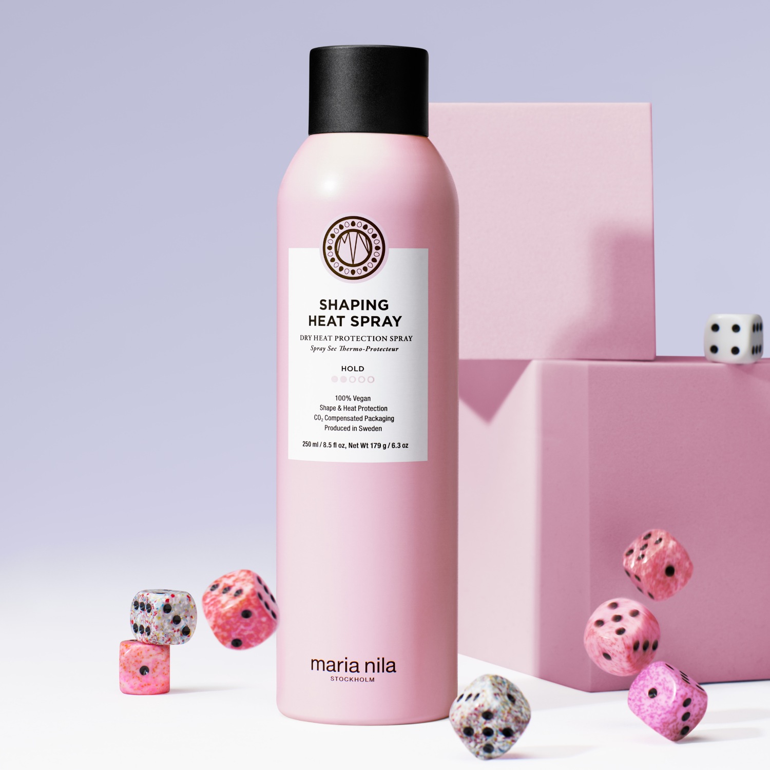 Rosa Maria Nila Shaping Heat Spray Flasche mit schwarzem Deckel, umgeben von rosa Würfeln, die Hitzeschutz und Formgebung versprechen.