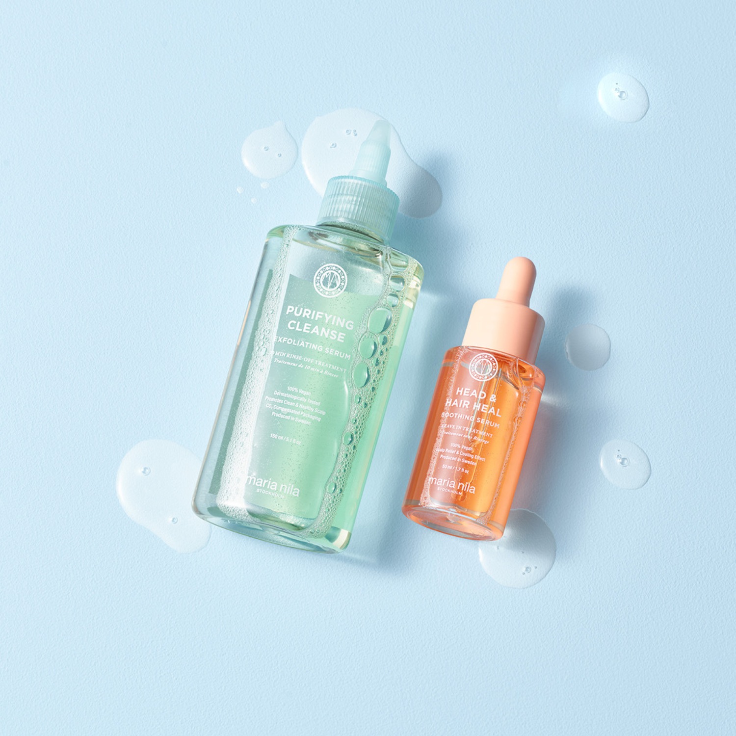 Auf hellblauem Grund liegen zwei Flaschen Maria Nila Haarserum: Die durchsichtige Flasche mit grünlichem Serum ist ein Peeling-Serum, die orangefarbene Flasche ein beruhigendes Serum.