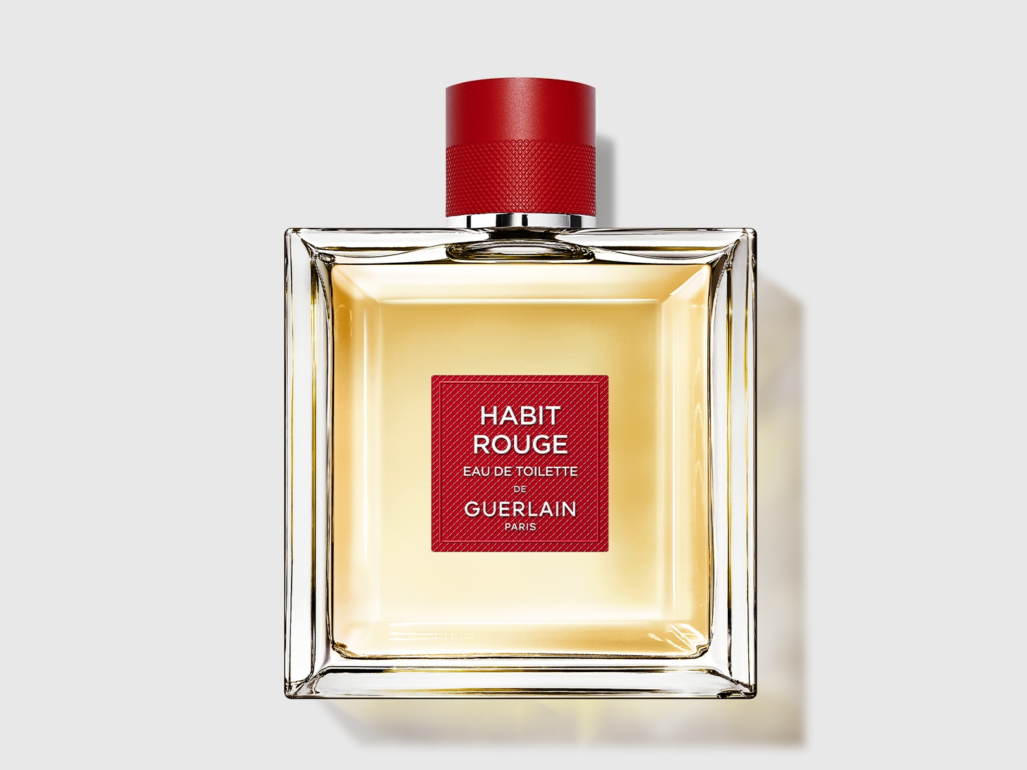 Voici Habit Rouge Eau de Toilette de Guerlain, un parfum ambré boisé pour homme, présenté dans un flacon transparent carré avec un bouchon rouge.