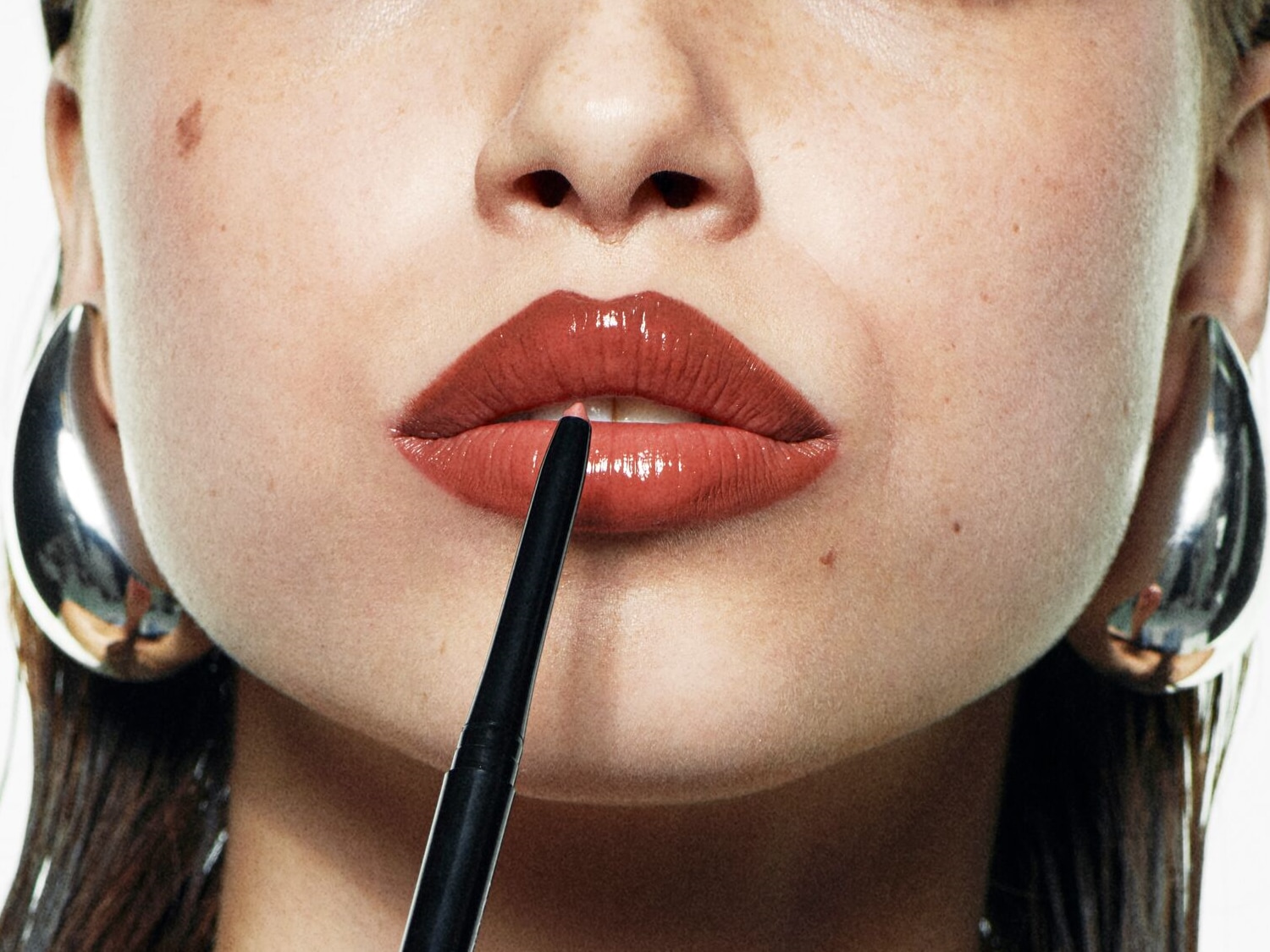 Nahaufnahme einer Frau, die einen Lippenstift mit einem schwarzen Lipliner aufträgt, um einen präzisen und vollen Look zu erzielen.