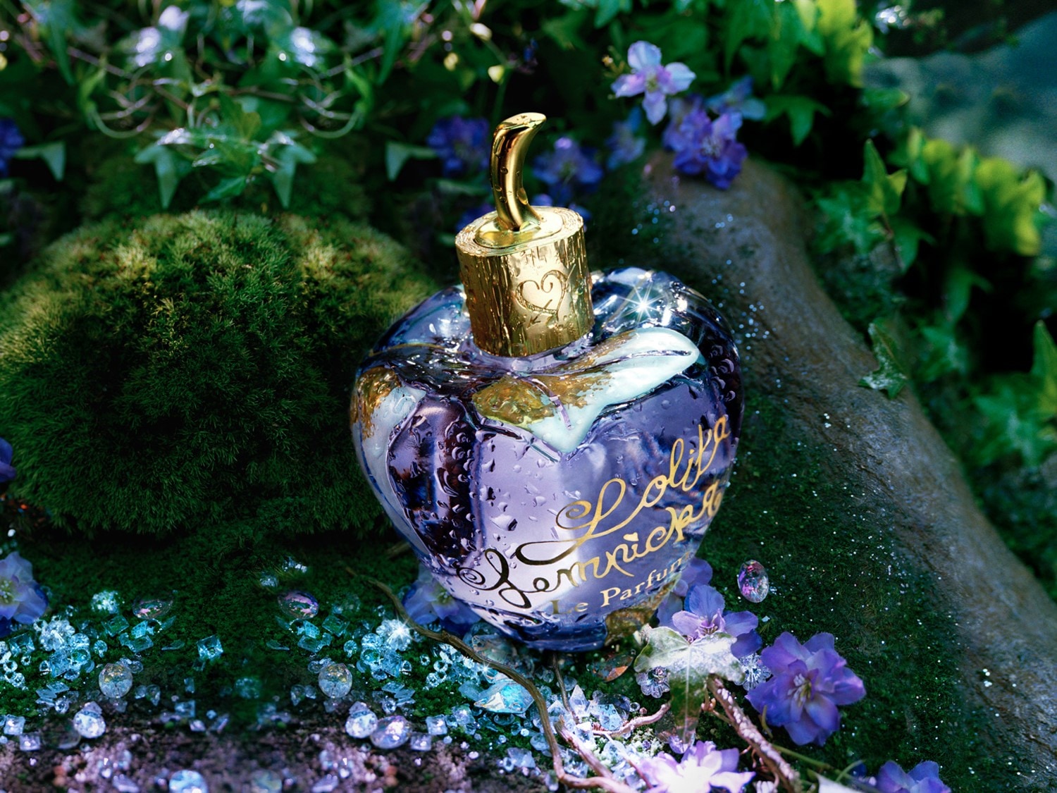 Le parfum Lolita Lempicka dans un flacon en forme de cœur violet et orné de fleurs, évoquant un jardin féerique.