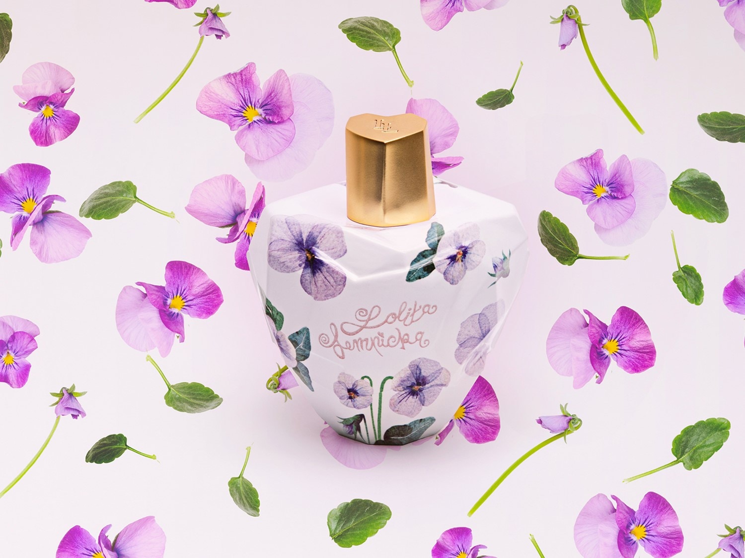 Découvrez le parfum Lolita Lempicka, un flacon blanc orné de fleurs violettes, coiffé d'un bouchon doré, évoquant un jardin printanier.