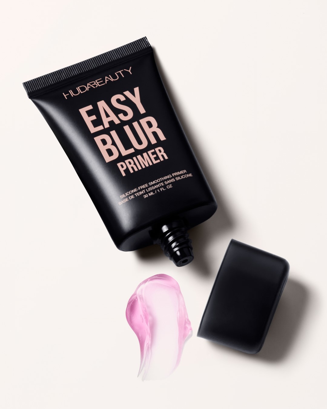 Die Huda Beauty Easy Blur Primer Tube in schwarz mit rosa Aufschrift und einem Klecks des rosa-schimmernden Primers daneben.