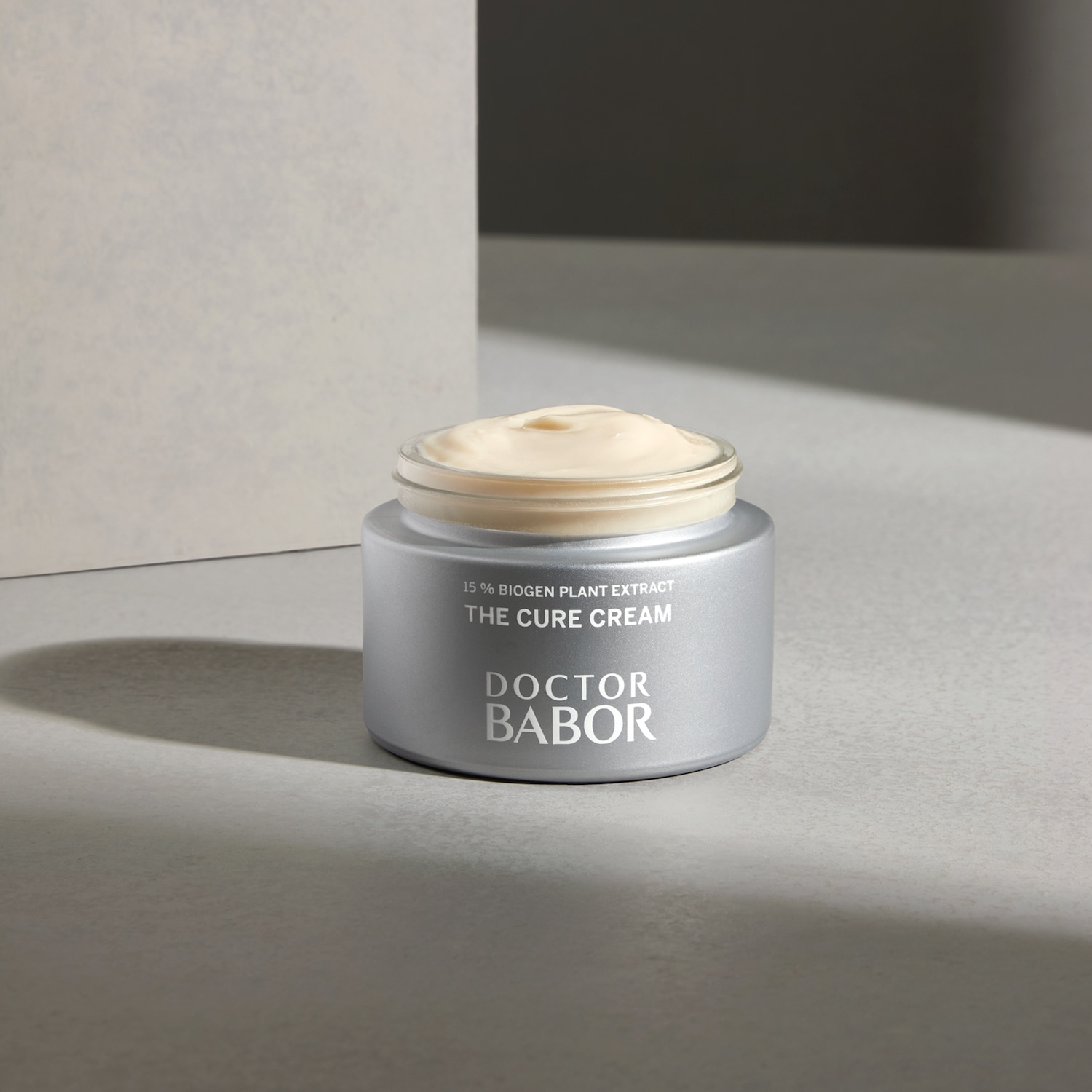 Srebrny słoiczek kremu Doctor Babor The Cure Cream z 15% ekstraktem z roślin biogennych, wypełniony beżowym kremem.