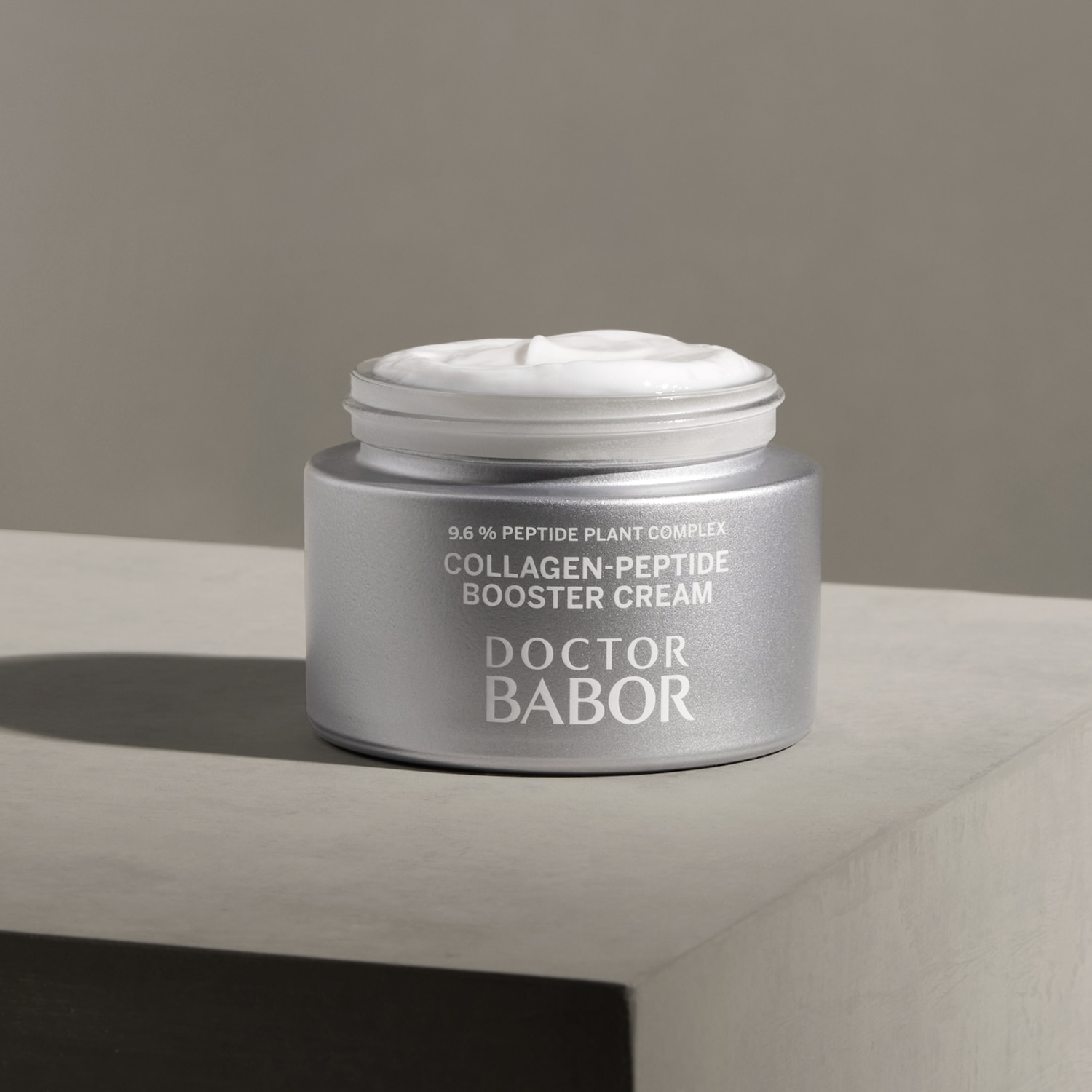 Srebrny słoiczek kremu Doctor Babor Collagen-Peptide Booster Cream z białą zawartością, obiecujący kompleks roślinny 9,6% dla wzmocnienia kolagenu.