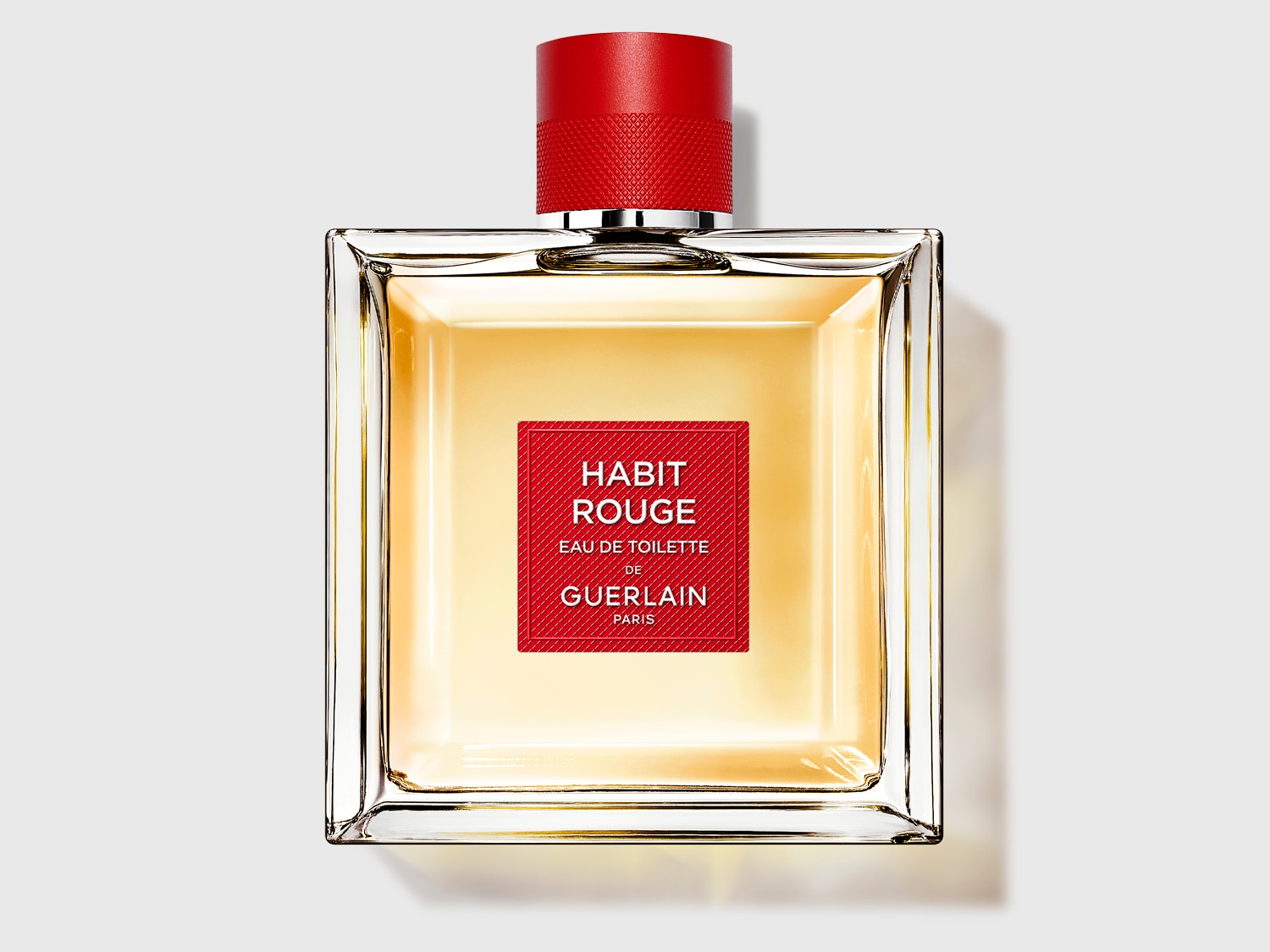 A Habit Rouge Eau de Toilette üvegben, piros kupakkal és címkével, elegáns megjelenést kölcsönözve.