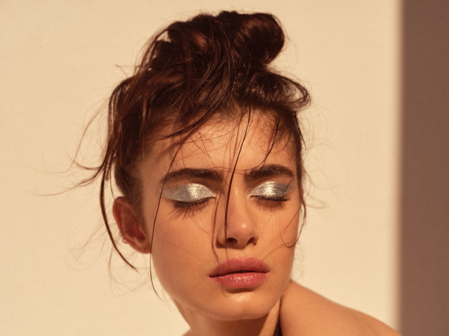 Portrét ženy so striebornými trblietavými očnými tieňmi a lesklými ružovými perami, vlasy má stiahnuté dohora.
