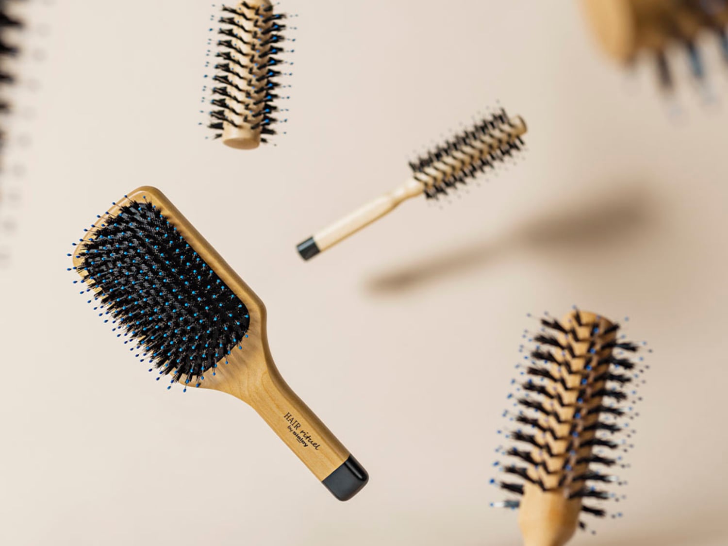 Diverses brosses à cheveux en bois flottent, avec des poils noirs et des pointes bleues, offrant une vue complète des outils de coiffure.