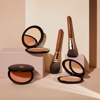 Kosmetické štětce s dřevěnou rukojetí a pudry v černých kompaktních pouzdrech, ideální pro dokonalý make-up.