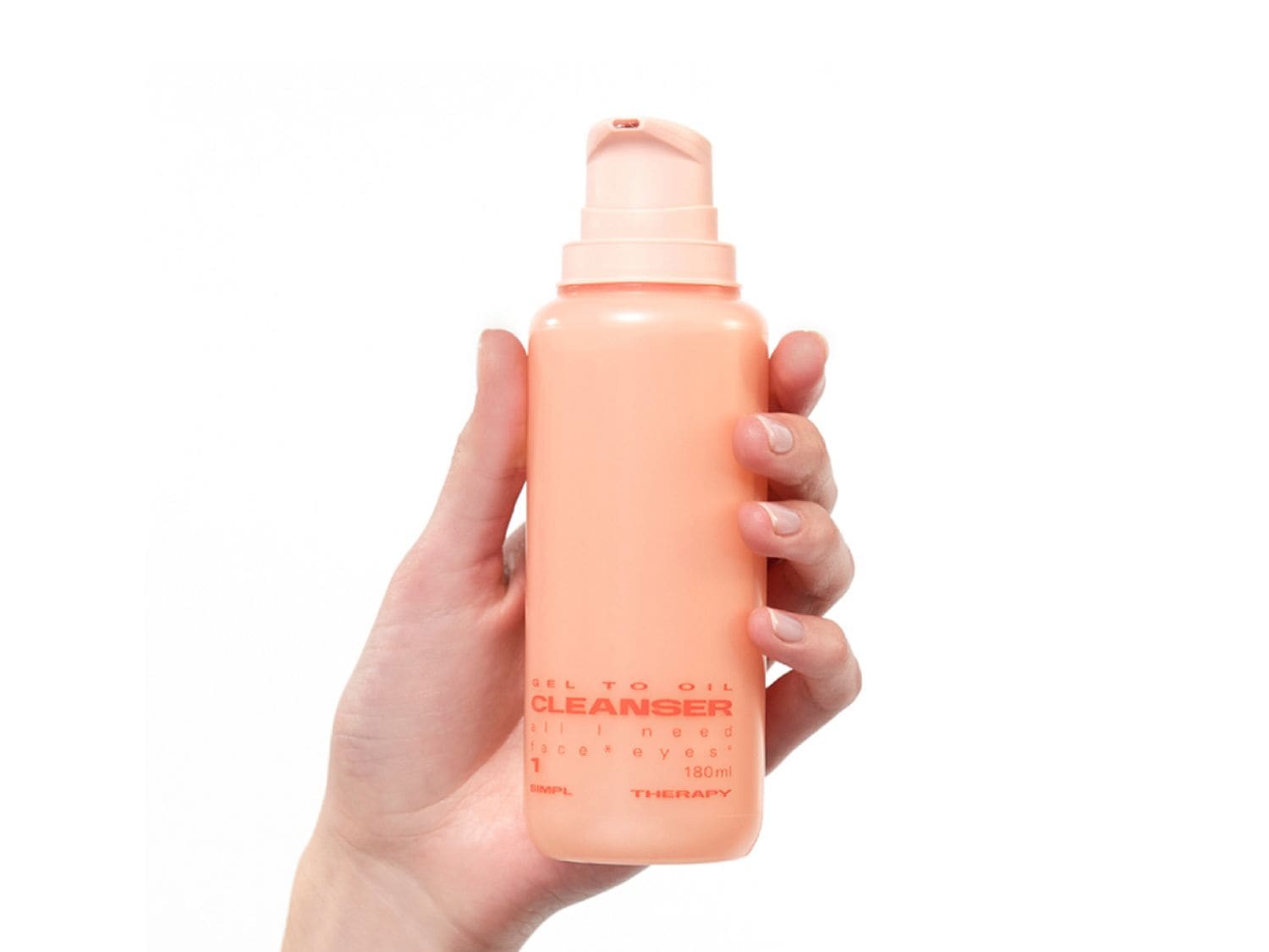 Egy kéz egy barack színű, 180 ml-es, pumpás arctisztító flakont tart, mely gélből olajjá alakuló állagú.