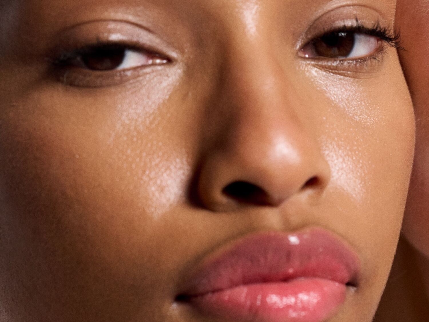Nahaufnahme eines Gesichtes mit glänzender Haut und vollen, glänzenden Lippen, die einen frischen und hydratisierten Look vermitteln.
