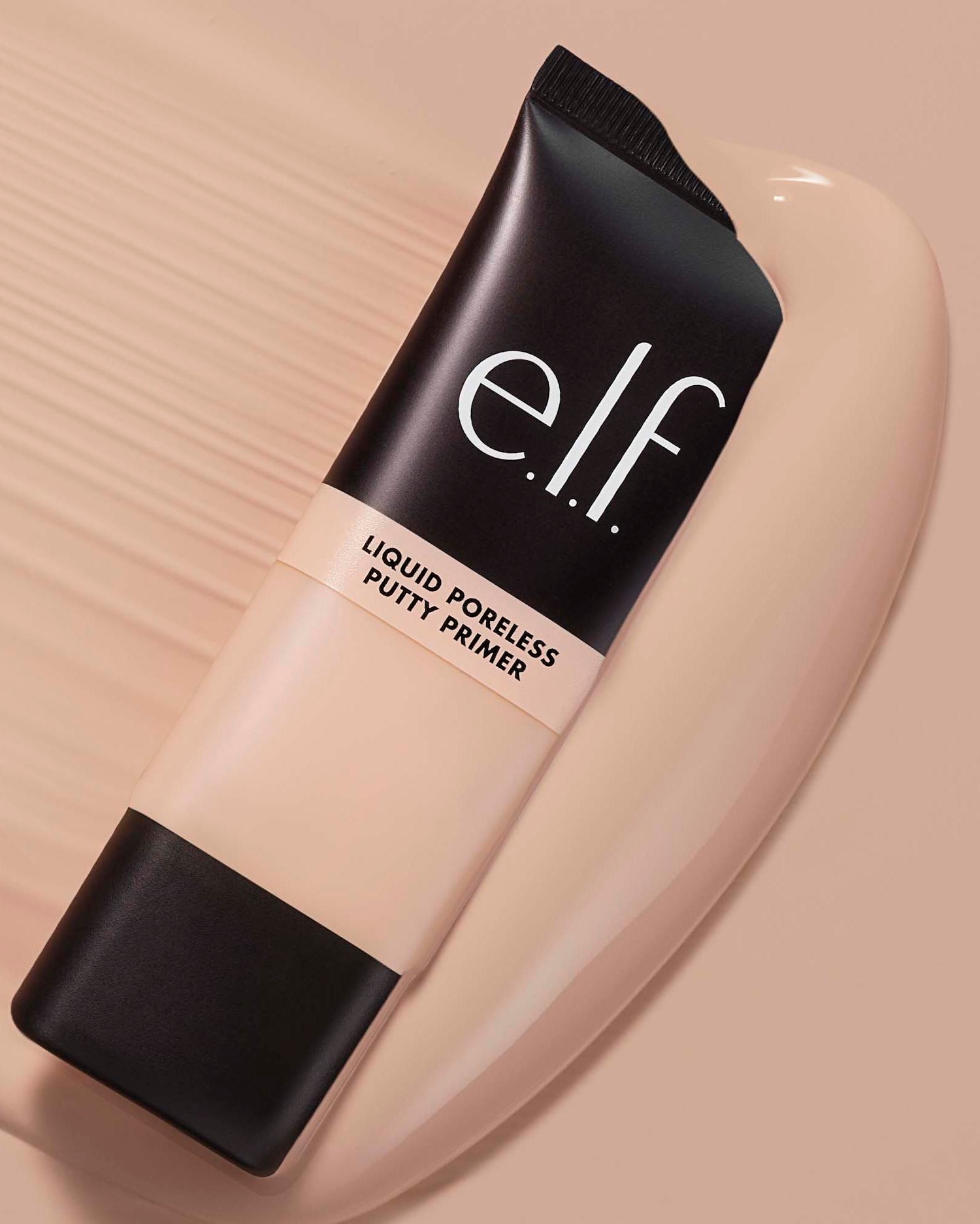 De e.l.f. Liquid Poreless Putty Primer in een tube met een zwarte dop en onderkant, liggend op een beige achtergrond.