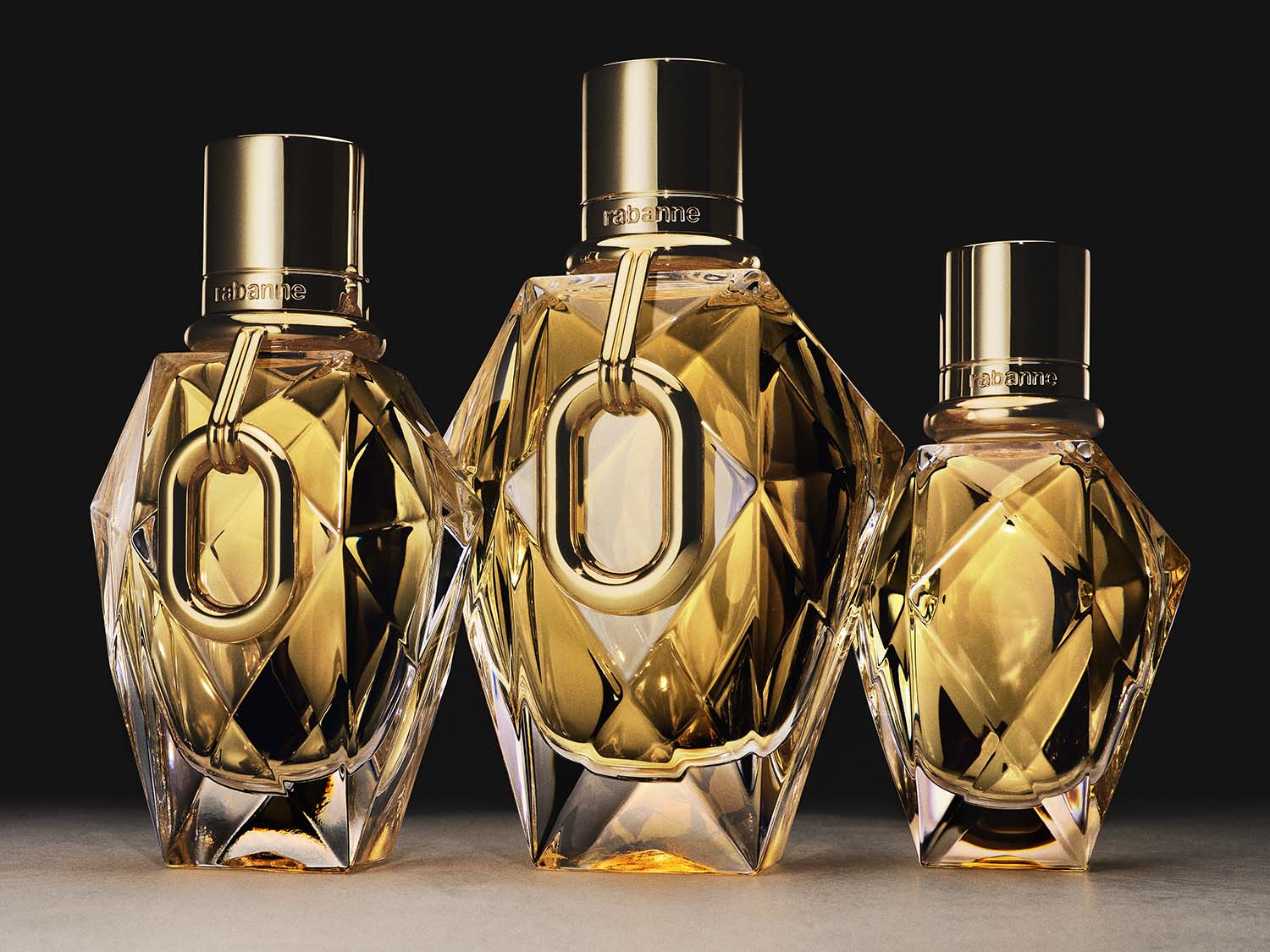 Nahaufnahme von drei goldenen, facettierten Flakons von Rabanne, die Eleganz und Luxus ausstrahlen.