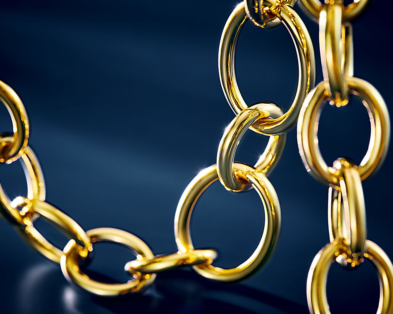 Błyszczący złoty łańcuch na ciemnym tle, tworzący luksusowy i elegancki akcent.