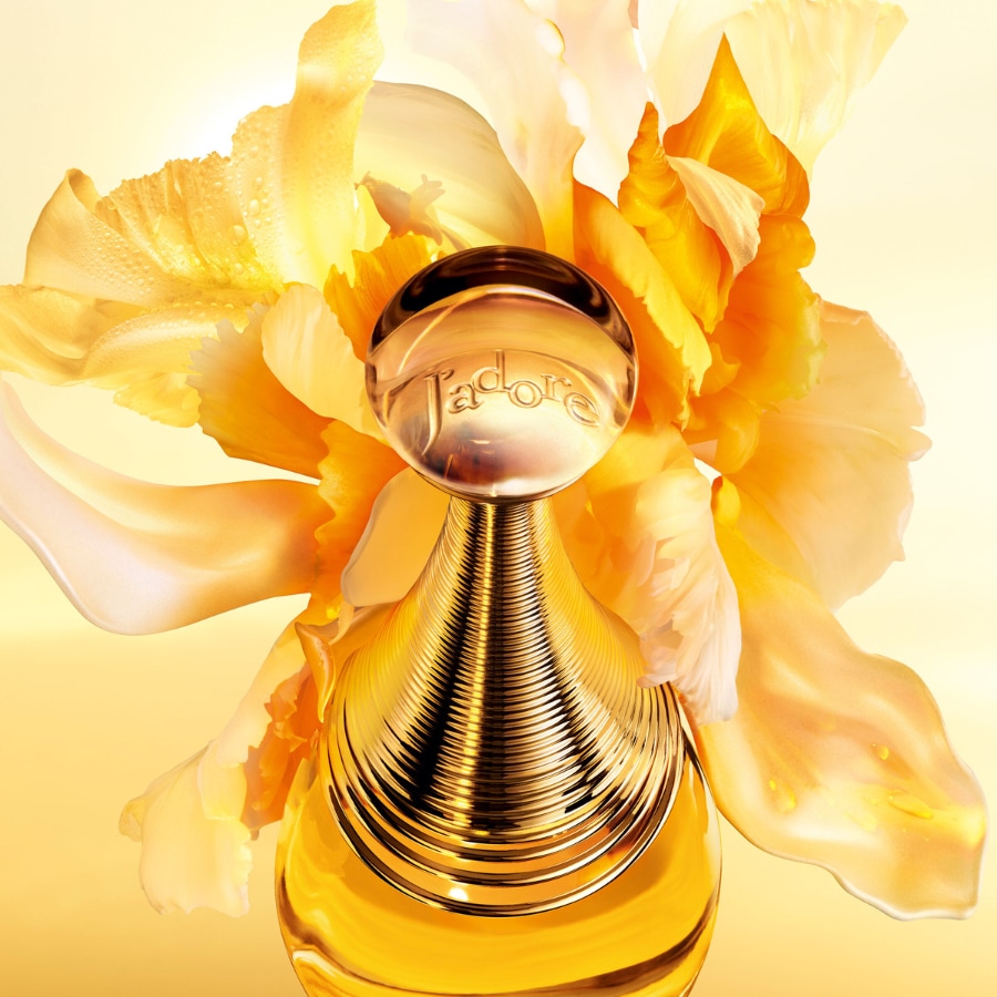 Découvrez J'adore, le parfum emblématique de Dior, dans un flacon doré élégant, sublimé par des fleurs jaunes éclatantes.