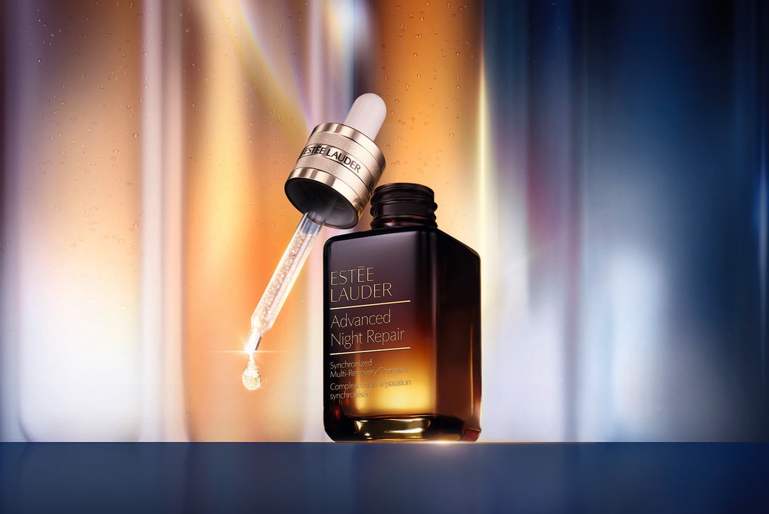 Ez az Estée Lauder Advanced Night Repair szérum, egy sötétbarna üvegben, arany felirattal, a pipettája pedig éppen egy cseppet adagol.