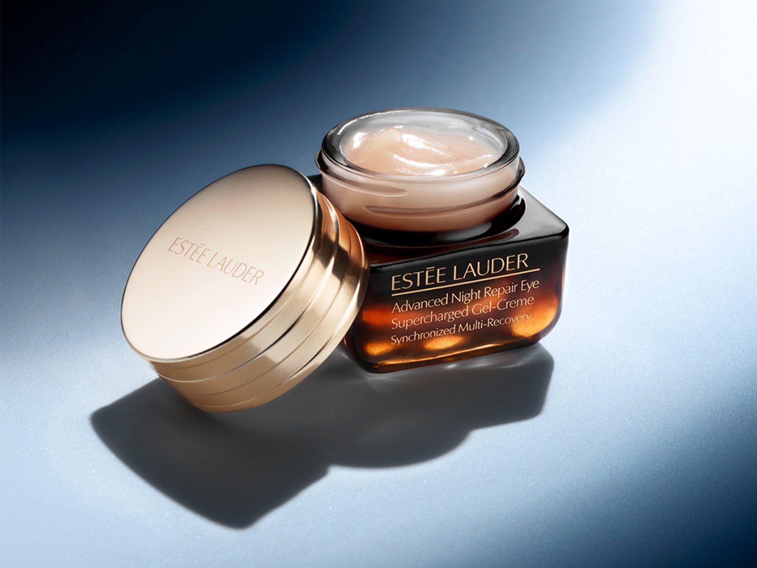 Estée Lauder Advanced Night Repair Eye Supercharged Gel-Crème in een bruine pot met gouden deksel, die een gladde, perzikkleurige crème onthult.