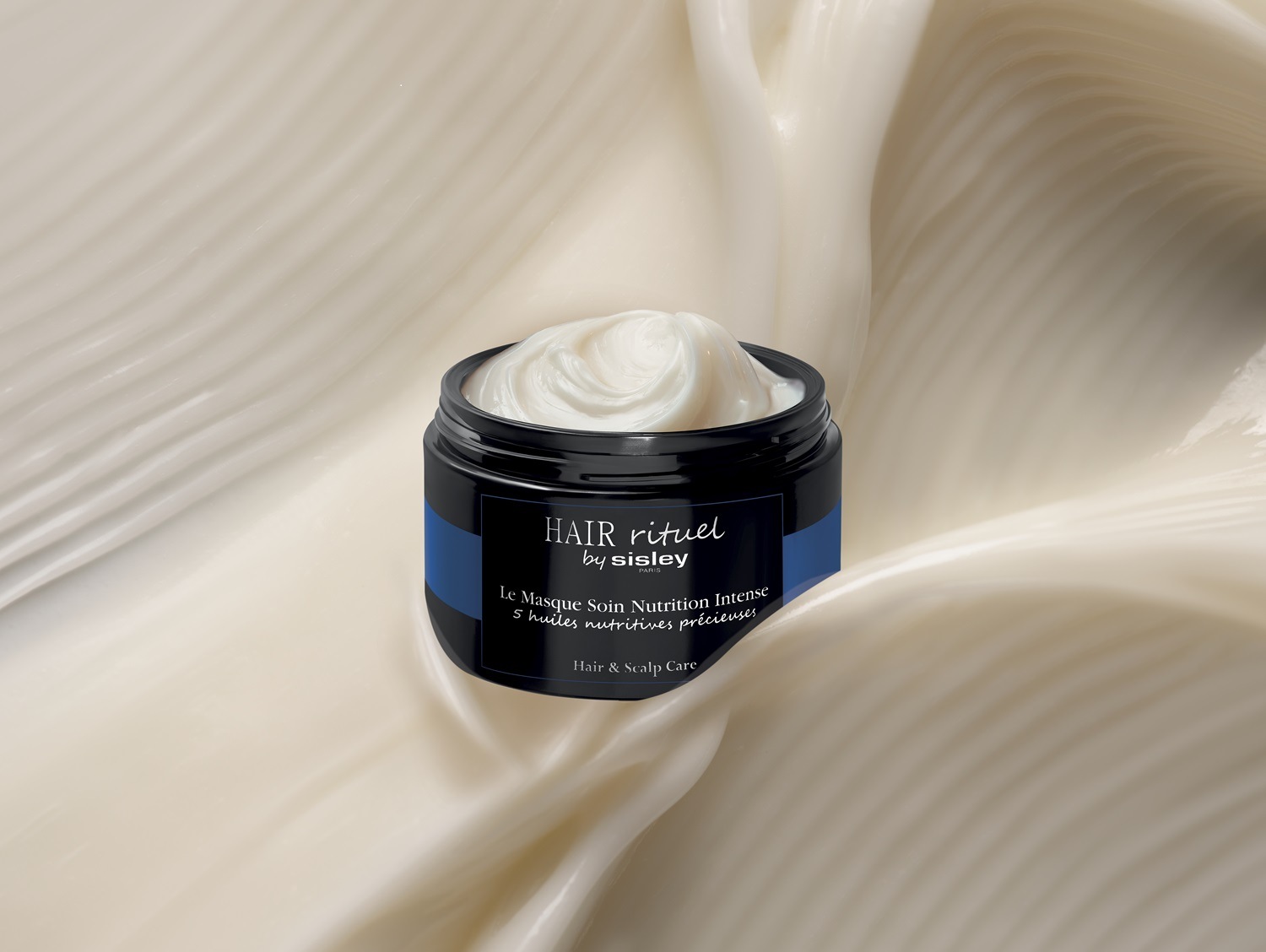 Maska do włosów Hair Rituel by Sisley Le Masque Soin Nutrition Intense w czarnym słoiczku z kremową zawartością, otoczona kremowym tłem.